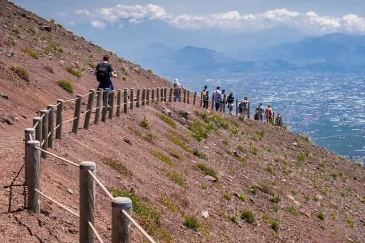 Tourists hike along the scenic trail on Mt. Vesuvius, offering panoramic views of Naples and the surrounding landscape.