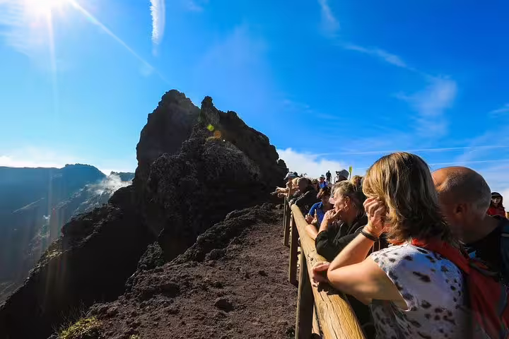 Tourists admire the stunning summit of Mt. Vesuvius under a clear blue sky during a day trip from Naples.