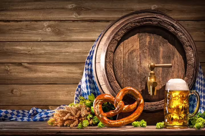 Wooden beer barrel with brass tap, pretzel, hops, wheat, and frothy beer mug on rustic table