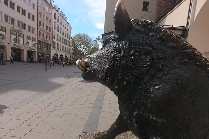 Bronze wild boar statue on a Munich pedestrian street with historic buildings in background