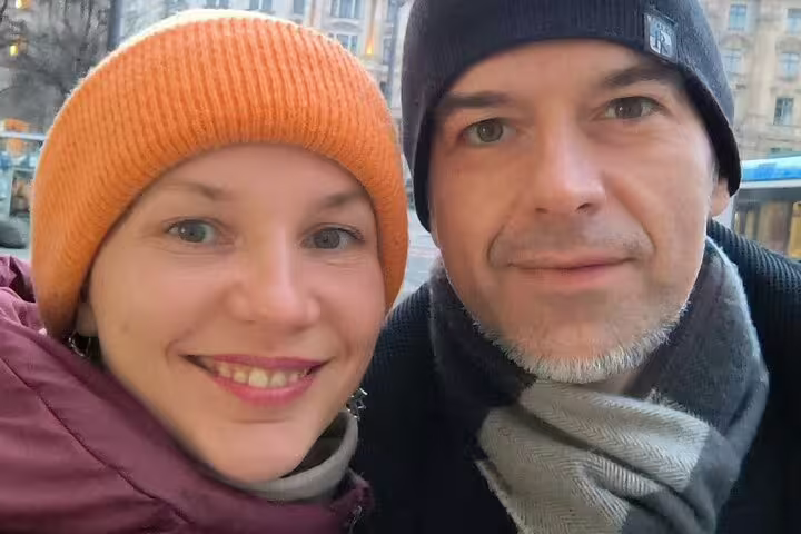 Couple in winter hats smiling outdoors in Munich city center during walking tour
