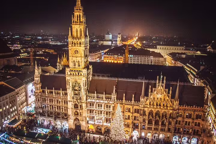 Aerial night view of Munich's illuminated Marienplatz town hall with Christmas tree and market below