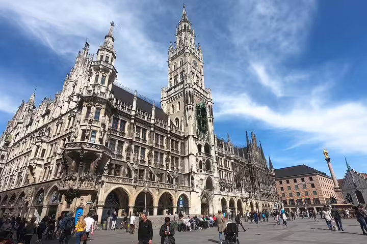 Gothic New Town Hall at Marienplatz square in Munich with tourists in foreground under blue sky