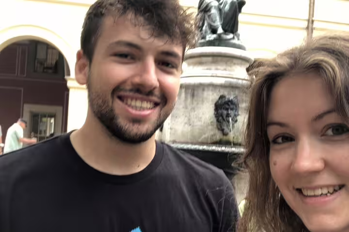 Two smiling tourists on a self-guided walking tour near a fountain in Munich Old Town