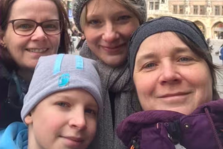 Group of three women and a child smiling together outdoors in Munich city center during winter