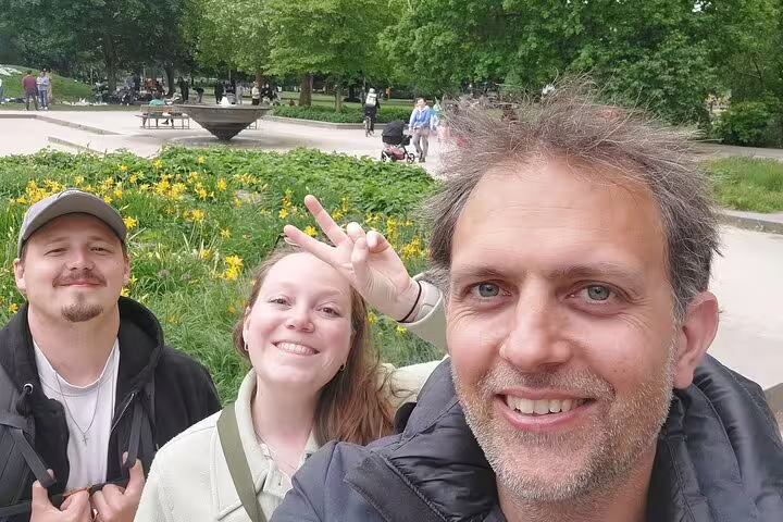 Three smiling tourists taking a selfie in a Munich park during a walking tour