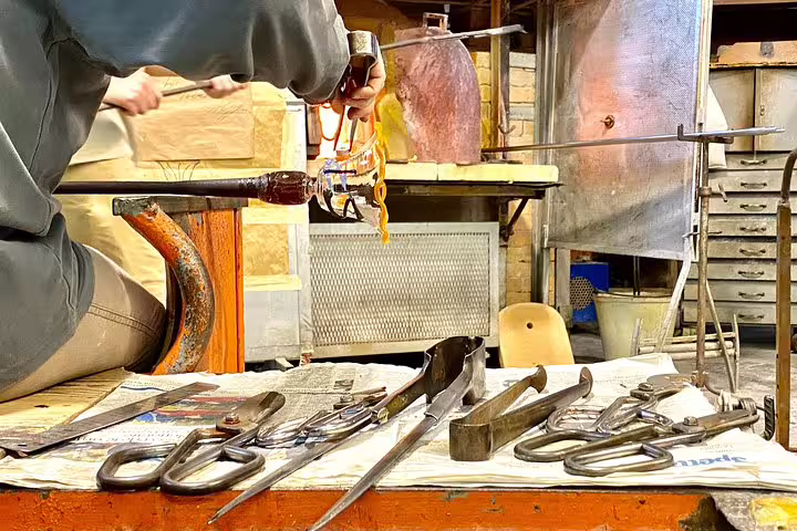 Artisan crafting intricate glass at a Murano workshop, showcasing traditional Venetian glassblowing techniques.