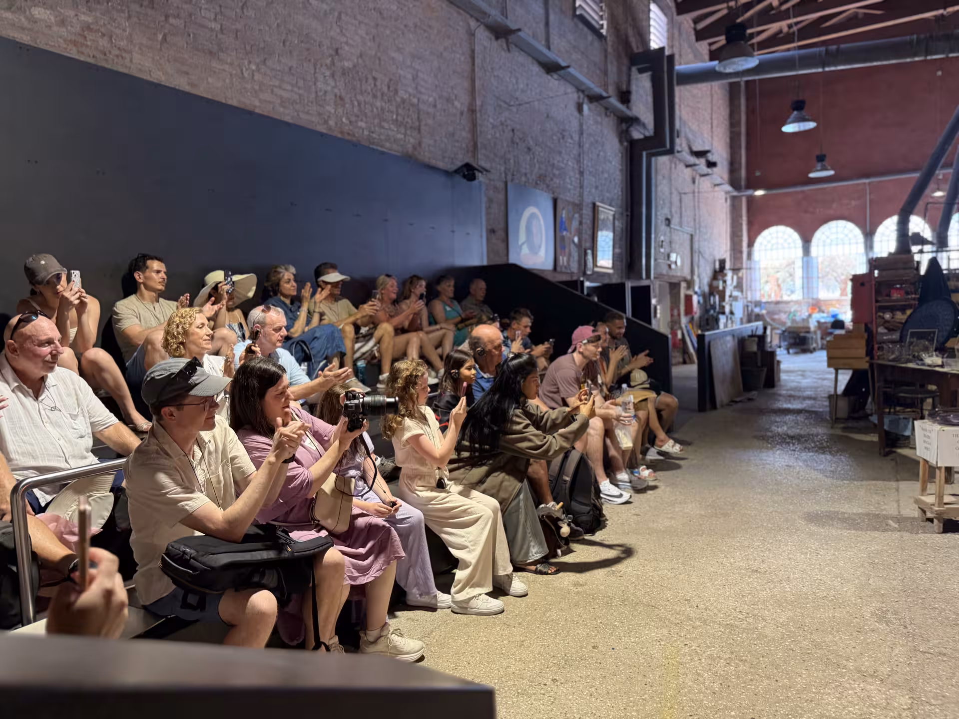 Tourists captivated by live glassblowing demonstration on Murano Island during Venice's guided speedboat tour.