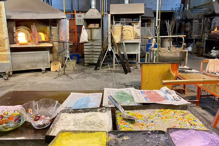 Colorful glass materials and furnaces in a Murano workshop on the Grand Canal boat tour from San Marco Square.