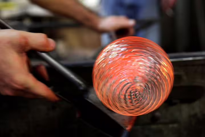Close-up of glowing hot glass being shaped by a skilled artisan in a Murano glassblowing studio in Venice.