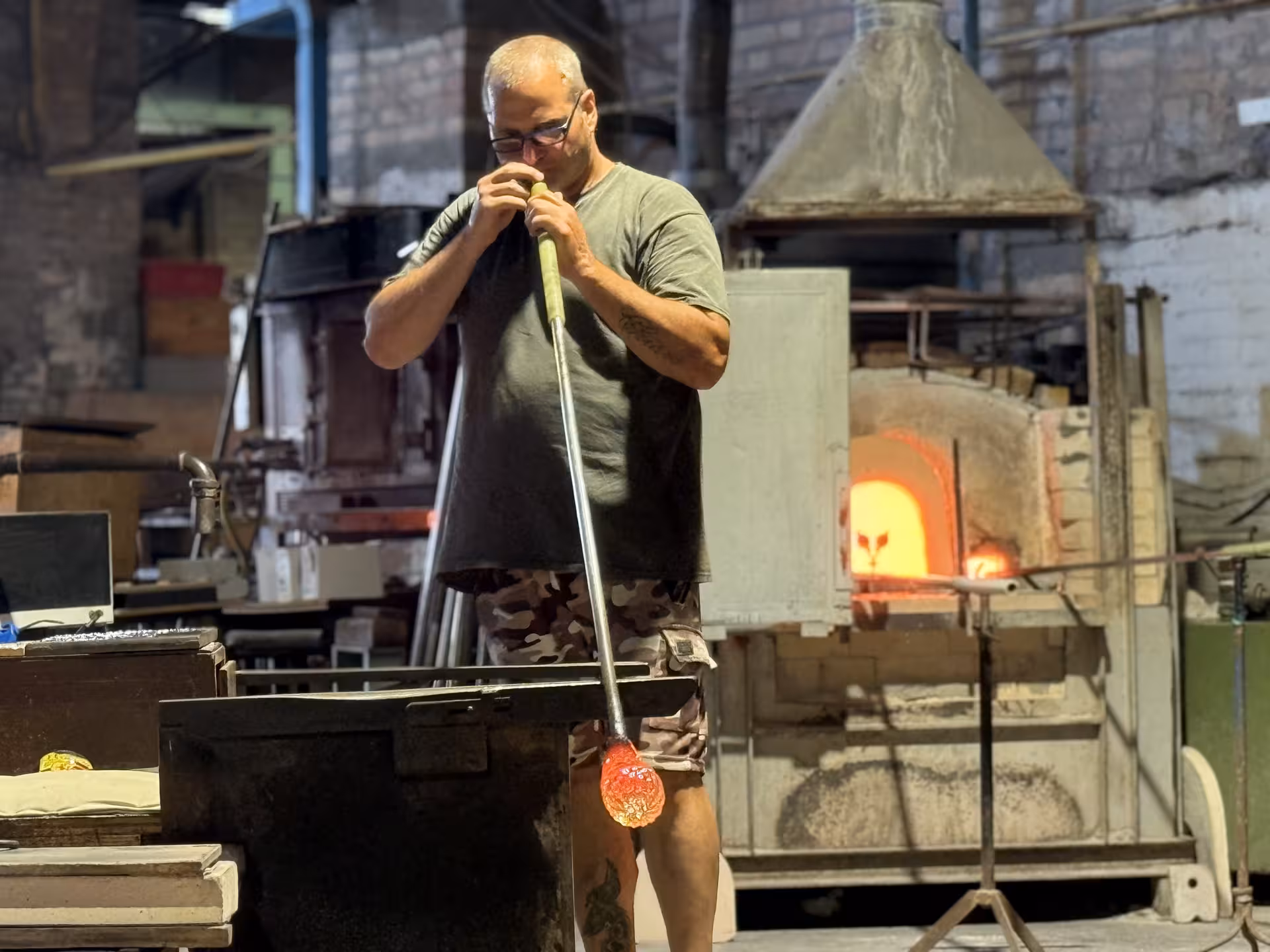 Murano glassmaker crafting art in a traditional furnace, showcasing Venetian glassblowing skills on guided speedboat tour.