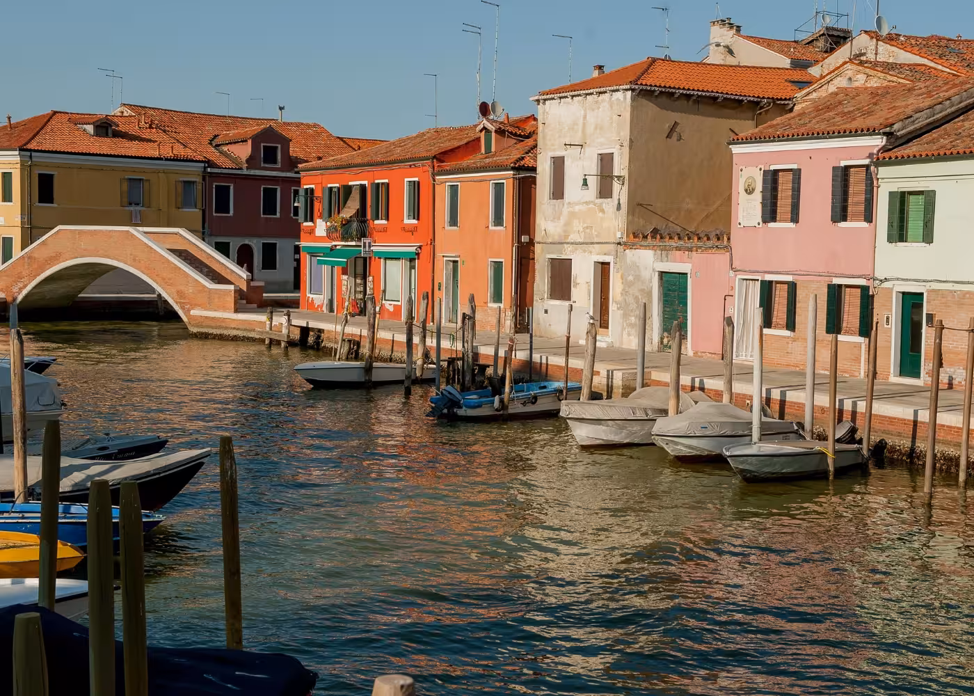 Charming canal with colorful houses and boats at Murano Island, capturing the serene Venetian atmosphere.