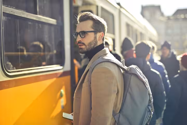 Business traveler with backpack waiting beside shuttle bus, representing reliable Muscat Airport transfer service