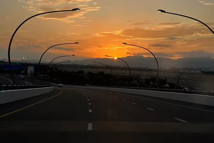 Scenic sunset view over an empty road leading to Muscat airport, perfect for airport taxi transfers.