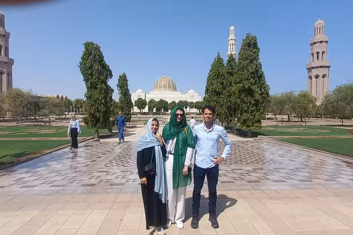 Tourists pose in front of Sultan Qaboos Grand Mosque gardens during a sunny half-day Muscat City sightseeing tour in Oman
