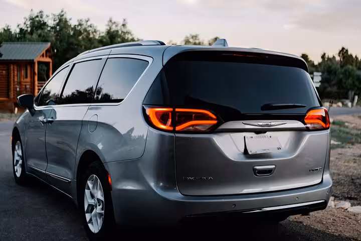 Modern air-conditioned minivan used for comfortable Muscat to Dubai private transfer, parked on a quiet roadside at dusk