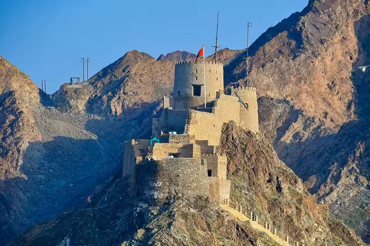 Historic Muscat fort perched on rocky mountain with Omani flag during private city tour Oman