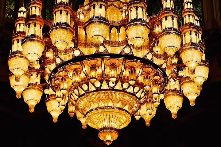 Luxurious chandelier with intricate glasswork illuminates a grand hall in Muscat, showcasing opulence and artistry.
