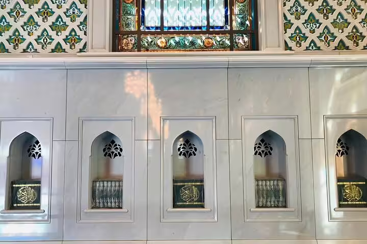 Discover intricate Islamic art and design inside Muscat's Grand Mosque, featuring decorative niches with religious texts.