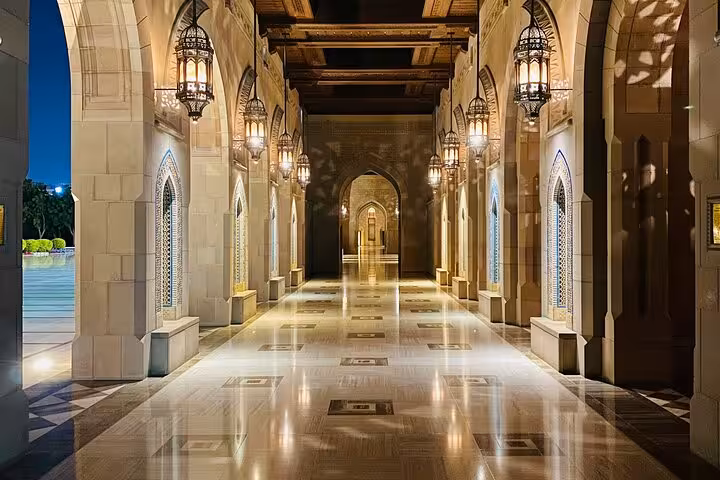 Elegant illuminated corridor with Islamic arches and hanging lanterns at a Muscat heritage site evening walking tour