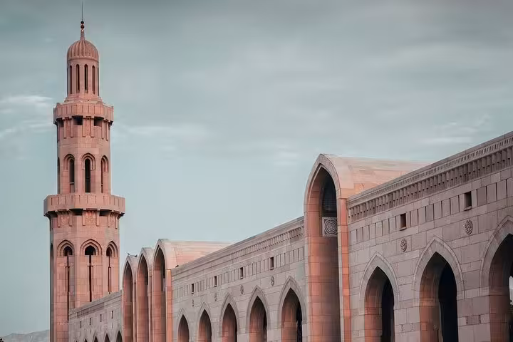 Elegant sandstone arches and minaret of a grand Muscat mosque, a highlight on private city sightseeing tours with transport