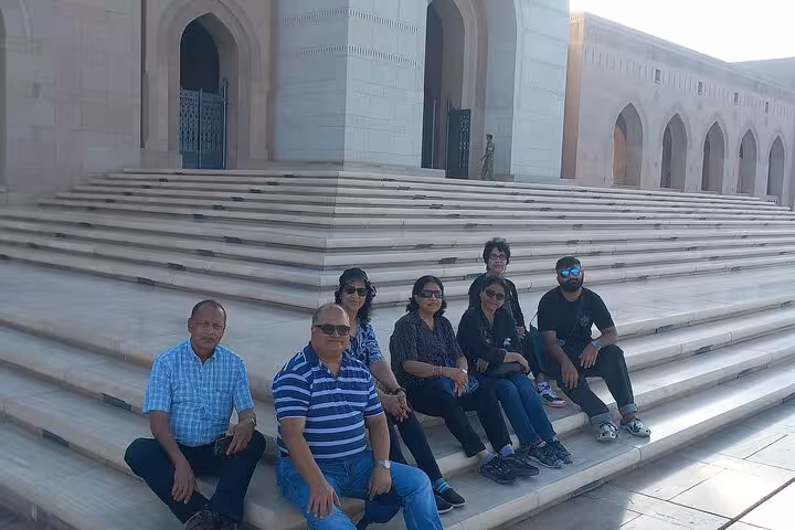 Tour group posing on marble steps of grand Muscat mosque during Old Quarter evening walking tour
