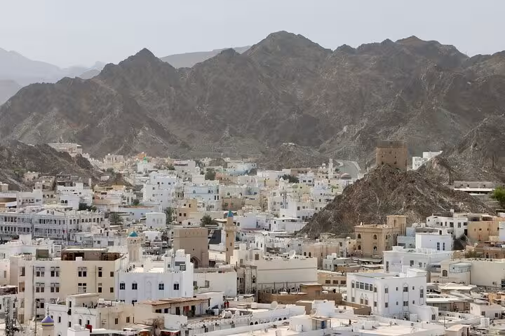 Panoramic view of Muscat’s whitewashed Old Town and rugged Hajar Mountains seen on a Premier Classic Muscat private cab tour