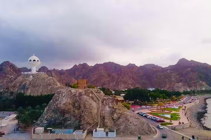 Experience Muscat's scenic beauty with mountain views, a striking white monument, and coastal charm on our Oman package tour.