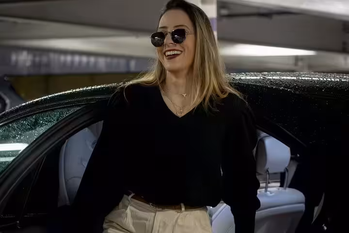 Happy female passenger exiting premium vehicle, showcasing comfort and style of Muscat private chauffeur transport service