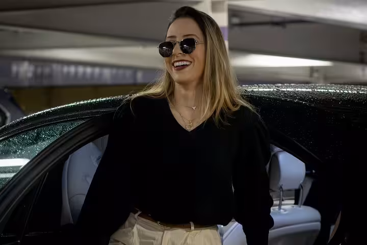 Smiling traveler stepping from a private car, enjoying comfortable door-to-door Muscat sightseeing tour with driver