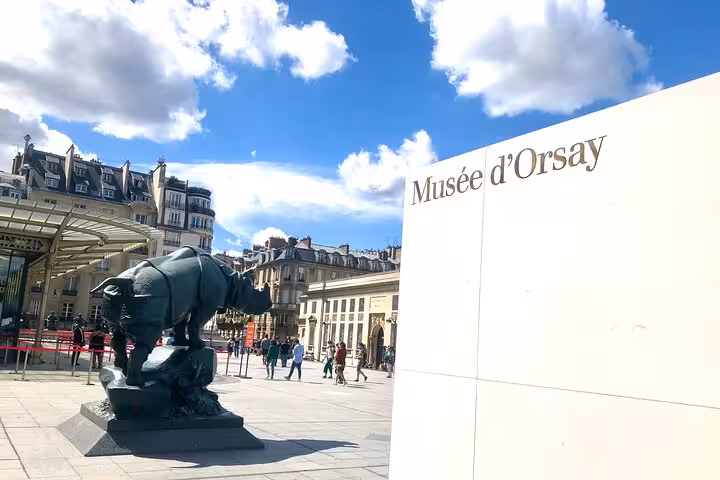 Musée d'Orsay entrance sign with bronze rhinoceros sculpture and Parisian buildings in background