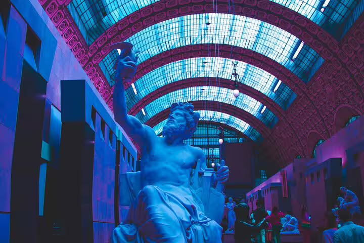Classical marble statue in the grand vaulted hall of Musée d'Orsay bathed in blue light