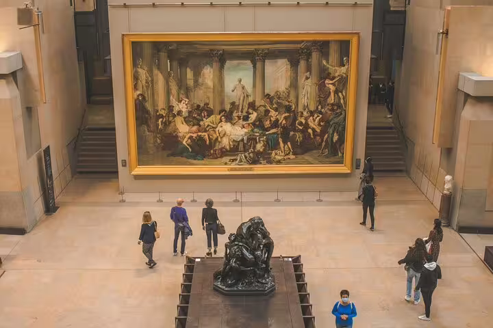 Visitors viewing large classical painting and Rodin sculpture in Musée d'Orsay grand hall