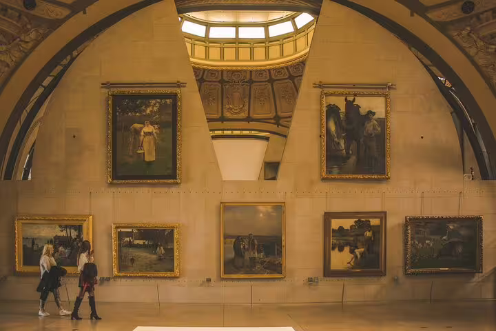 Visitors viewing classic paintings in grand arched gallery hall at Musée d'Orsay, Paris