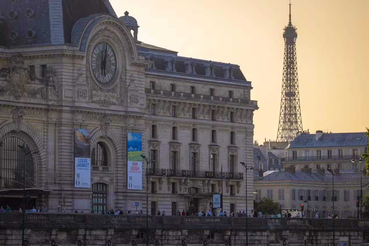 Musée d’Orsay façade with clock and Eiffel Tower at golden hour, highlighting central Paris location for private tours