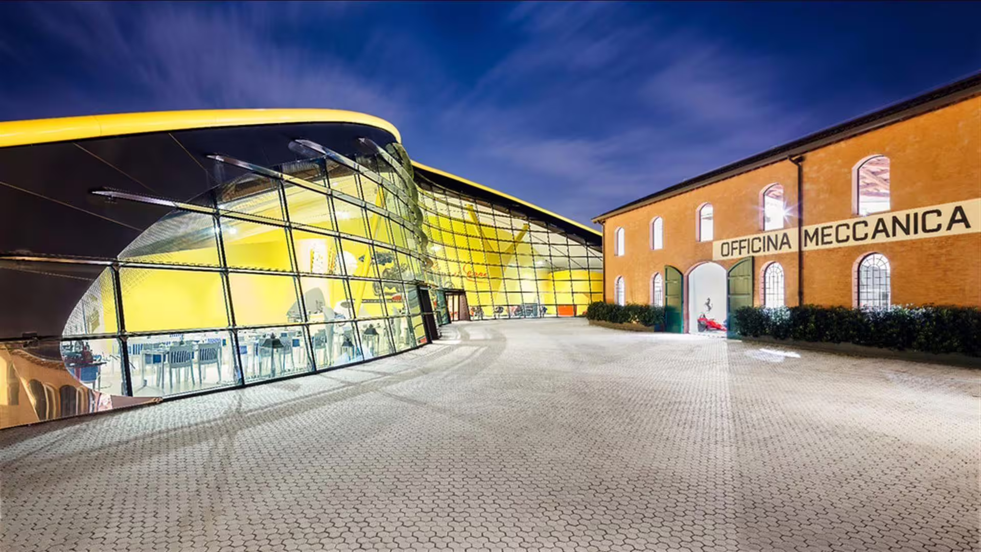 Museo Enzo Ferrari Modena exterior at dusk, glass pavilion and Officina Meccanica on combo tour