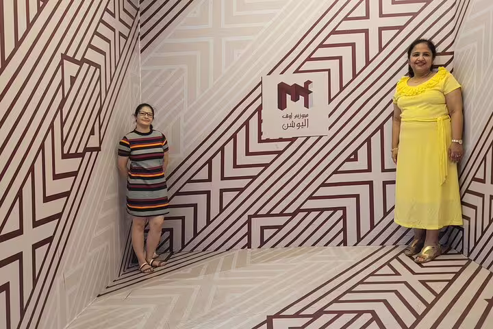 Two women posing in a geometric optical illusion room at the Museum of Illusions