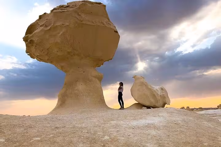 Traveler beside the Mushroom Rock in Egypt’s White Desert on a 3 days Eco Bahariya Oasis camping tour at sunset