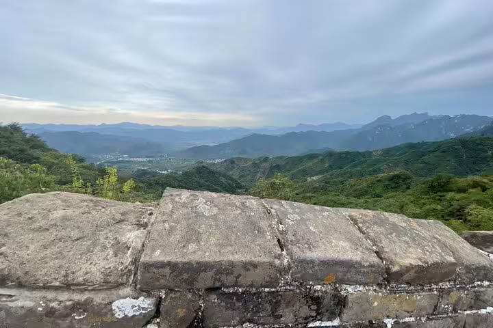 Expansive vista from Mutianyu Great Wall showcasing rolling green mountains and distant valleys, ideal for sightseeing.