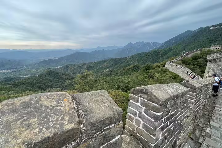 Panoramic view along Mutianyu Great Wall with mountainous backdrop and lush greenery, perfect for a guided day tour.