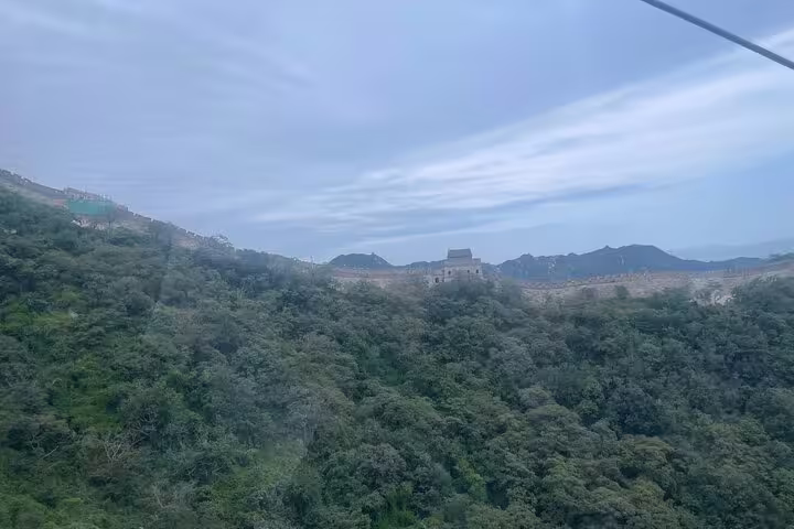 Scenic view of Mutianyu Great Wall winding through lush green hills under a cloudy sky, perfect for a private day trip.