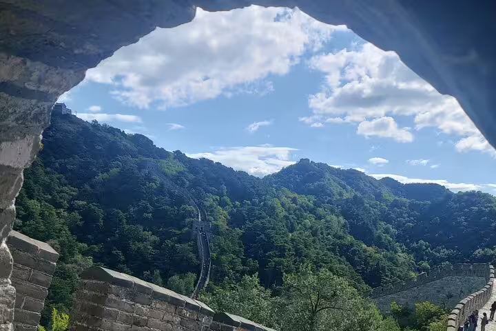 Scenic view of Mutianyu Great Wall surrounded by lush green hills under a blue sky, perfect for a private day tour.