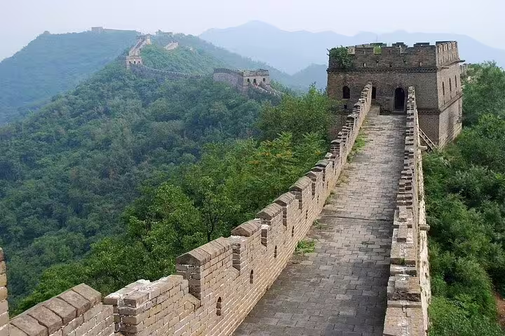 Scenic view of Mutianyu Great Wall's ancient watchtower and lush greenery, ideal for a guided day tour.