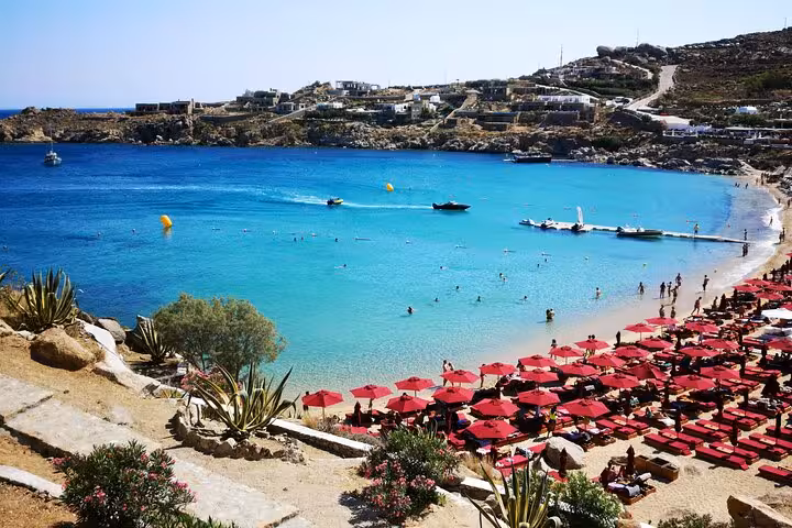 Panoramic Mykonos beach bay with turquoise water and red umbrellas, seen on a private countryside tour