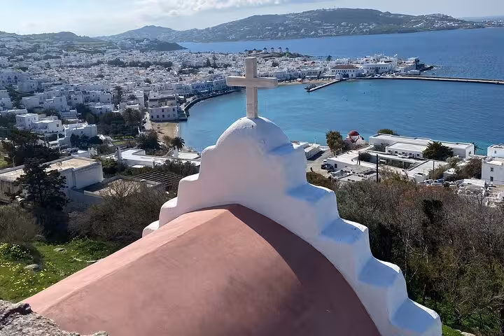 Church dome with cross above Mykonos Town and turquoise bay, panoramic viewpoint on a private half-day tour