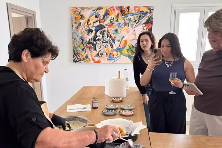 Local chef plating Greek meze during an authentic Mykonos cooking class as guests sip wine and watch