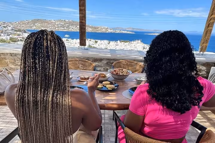 Guests enjoy homemade Mykonian meal with sea views after a cooking class, ideal Mykonos cruise excursion