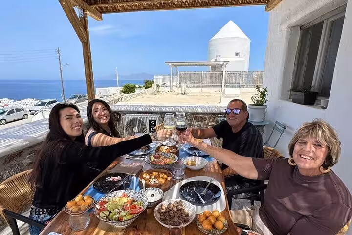 Guests toast with wine after Mykonian cooking class, enjoying Greek meze lunch on a sea-view terrace