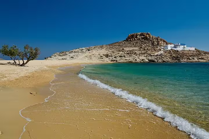 Quiet Mykonos hidden beach with golden sand, clear water and rocky hill, ideal for secluded bays tour