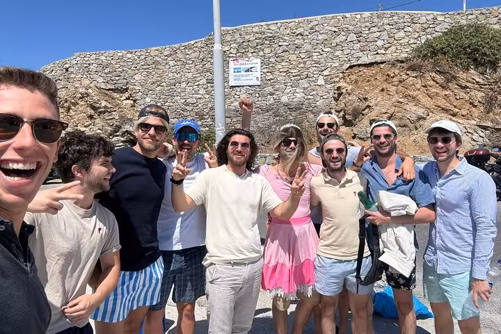 Happy group photo on Mykonos private island half-day tour, friends posing by coastal cliffs in Greece
